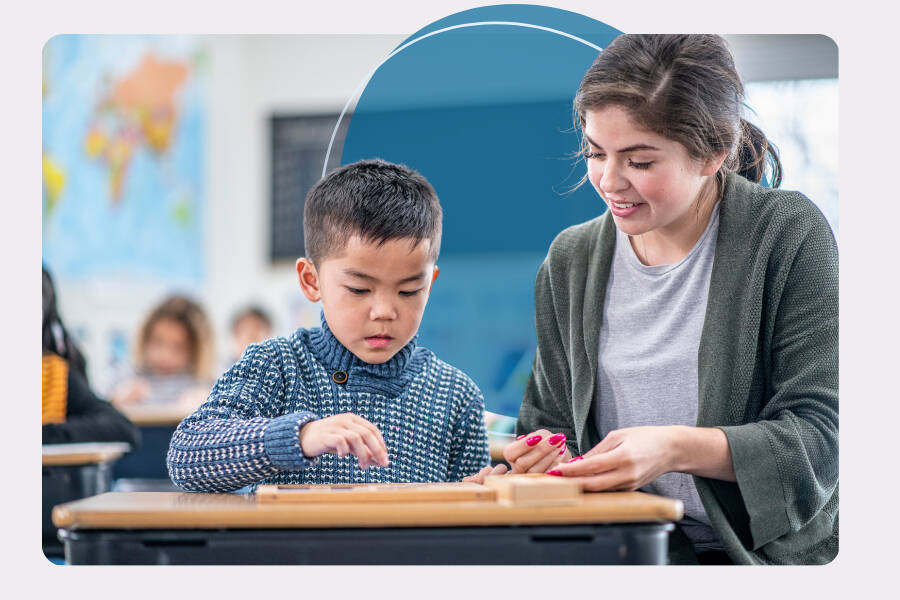 Teacher supporting a young student during a classroom learning activity.